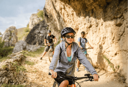 Group cycling on electric bikes along rocky trail, outdoor adventure from Pogo Cycles