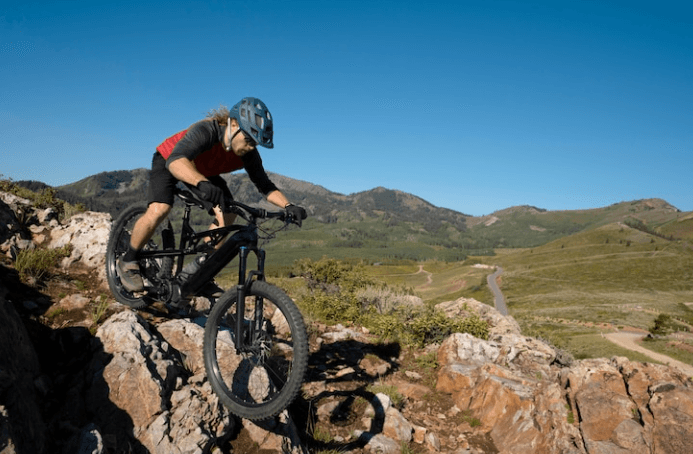 Black electric mountain bike side view ridden on rocky trail in outdoor landscape