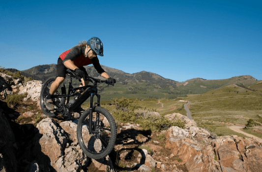 Black electric mountain bike side view ridden on rocky trail in outdoor landscape