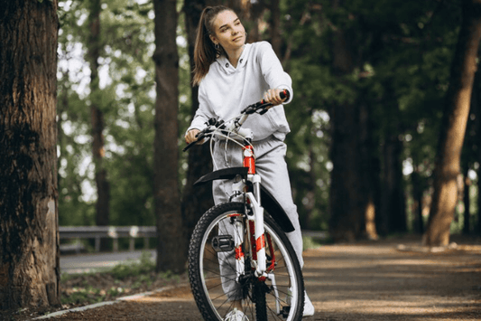 Woman in grey activewear with electric bike on forest path, Pogo Cycles e-bike for women