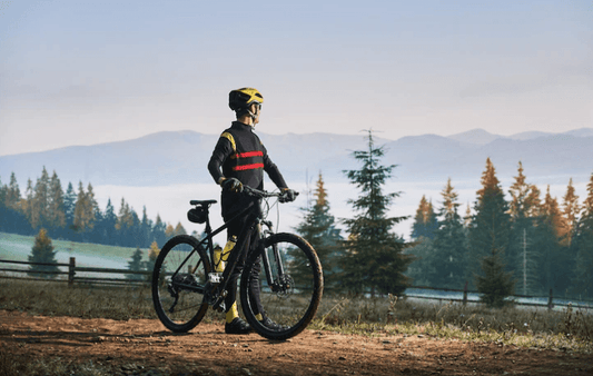 Electric mountain bike side view with rider on forest trail, wearing yellow helmet and gear