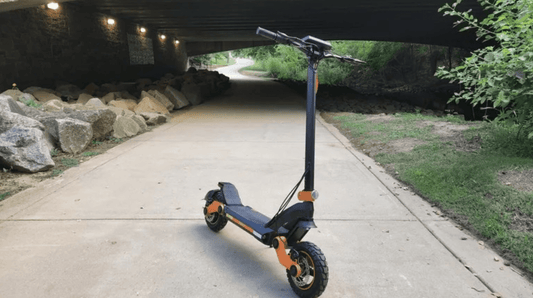 Electric scooter with orange accents on a paved path under a bridge, side view