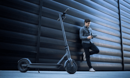 Electric scooter with man using tablet outside modern building at Pogo Cycles e bike store