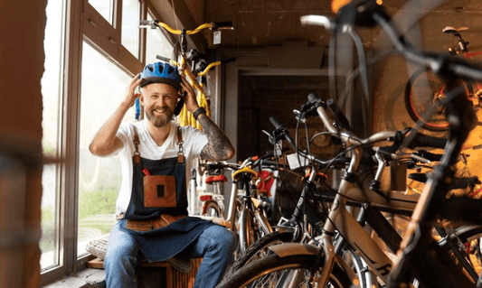 Electric bikes lined up in a bike store with a smiling man adjusting a helmet, indoor setting