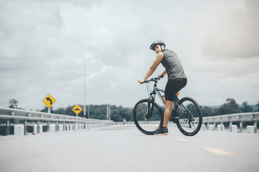 Electric bike in matte black with rider, side view, on an open road outdoors