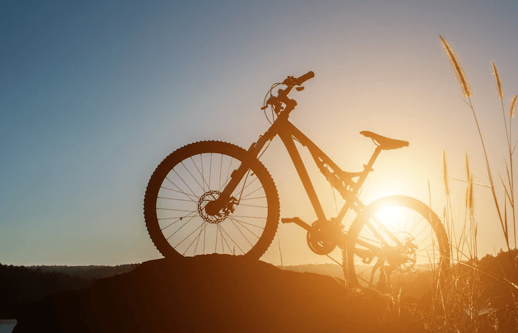 Full suspension electric bike side view on a hill at sunset, outdoor lifestyle scene